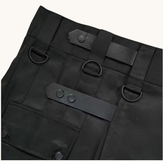 Close-up of black pants with leather straps and buttons on a white background